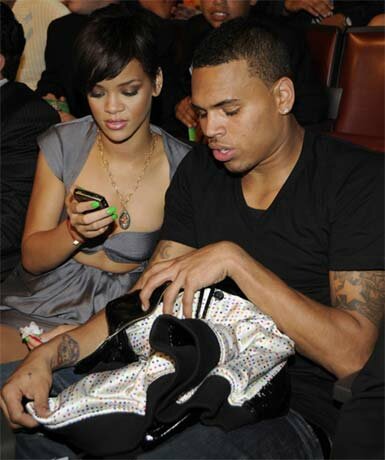 Photo of Chris Brown with Rihanna looking through cellphone.